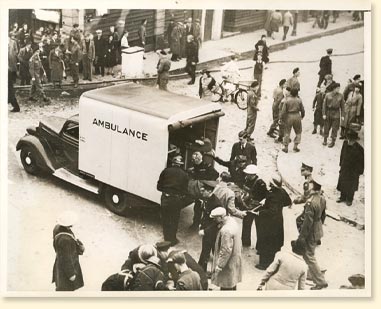 Des victimes sont places dans une ambulance par des engags de la dfense passive aprs un raid de bombardement allemand sur la ville d'East Anglia, Angleterre, 1940. Rfrences photographiques : Acme Newspictures Inc.