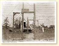 After supper a bugle call announces that the gate is open for fishing or a walk along the river. Here the camp spokesmen watch the signing-out and will see that every man returns. They post their own sentries outside to see that no one wanders. - AN19830444-052 - Canadian Army Photo  2907-1