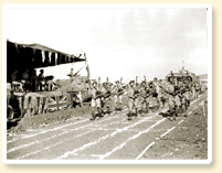 Les cornemuseurs du 48th Highlanders of Canada, une unité d'infanterie de Toronto (Ont.), divertissent l'assistance présente à une rencontre d'athlétisme pendant une période de repos durant la bataille de la Sicile, 23 août 1943. - Photo : Armée canadienne No 23196, CWM Reference Photo Collection