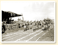 The pipers of the 48th Highlanders of Canada, an infantry unit from Toronto, Ont., entertain at a Canadian Army track and field meet during a rest period in the battle for Sicily, 23 August 1943. - Canadian Military Photograph, No 23196, CWM Reference Photo Collection