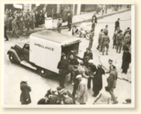 Des victimes sont placées dans une ambulance par des engagés de la défense passive après un raid de bombardement allemand sur la ville d'East Anglia, Angleterre, 1940. Références photographiques : Acme Newspictures Inc.