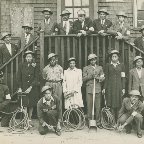 Un groupe de bénévoles afro-canadiens, hommes et femmes, pose avec des casques Mark II et des boyaux.