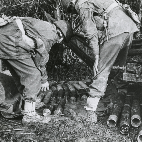Deux soldats se penchent en empilant des munitions.