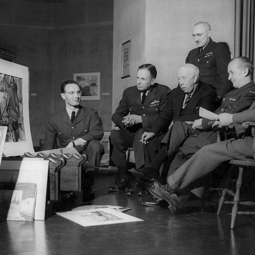 Sept hommes sont assemblés autours de plusieurs œuvres terminées, en discutant.