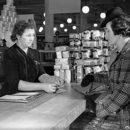 Une femme achète de la nourriture avec des coupons de rationnement d'une employée.