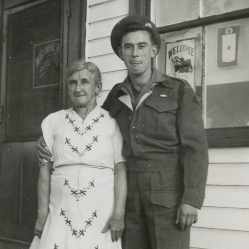 Le soldat et sa mère à l'extérieur de leur maison.