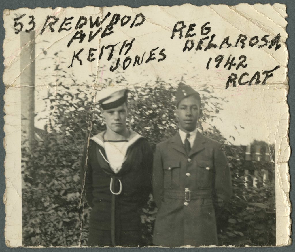Un Blanc en uniforme de la marine se tient à côté d’un Noir en uniforme de l’aviation. Un texte manuscrit identifie les hommes.
