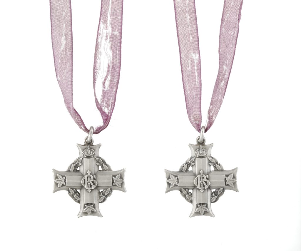 Deux croix en argent sur des rubans violets, chacune portant le monogramme royal du roi George V, « GRI » au centre et des feuilles d’érable à l’extrémité de trois bras.