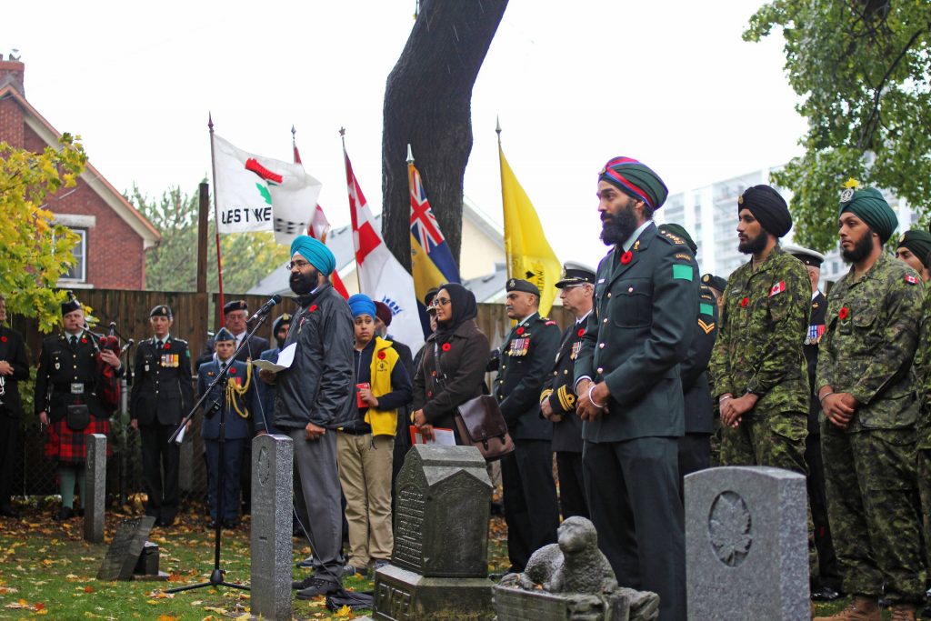 Une cérémonie dans un cimetière, en présence de militaires sikhs et d’autres personnes.