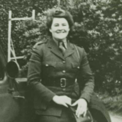 Une femme en uniforme assise à côté d'une voiture au Musée canadien de la guerre à Ottawa.