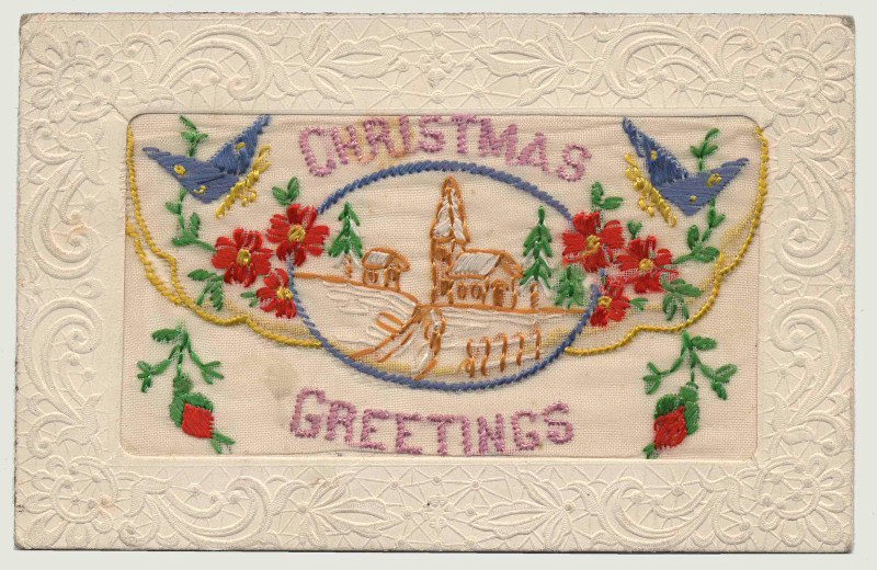 Broderie rectangulaire représentant une scène hivernale entourée de fleurs rouges et de papillons bleus, ainsi qu’un texte violet indiquant « Vœux de Noël », le tout entouré d’une bordure blanche ornée.