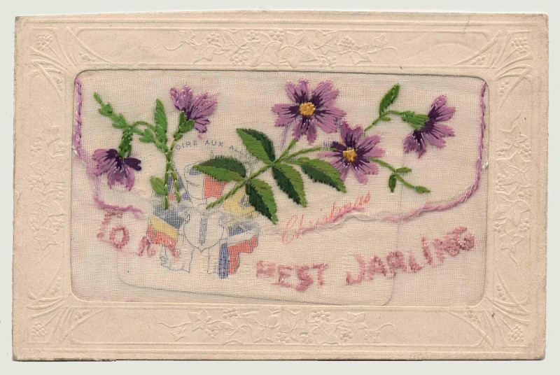 Broderie rectangulaire représentant des fleurs violettes avec des feuilles vertes, ainsi qu’un texte violet indiquant « À ma chère bien-aimée ».