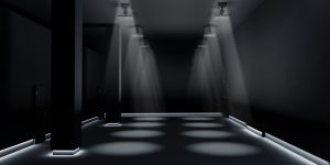 Une pièce sombre avec deux rangées de projecteurs qui éclairent à partir du plafond et des bandes lumineuses au bas des murs.