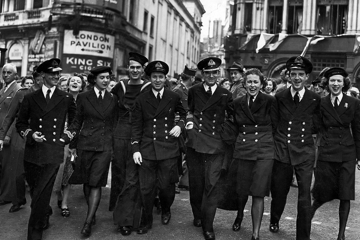 Photographie d’un groupe de personnel de service souriant et marchant en ligne large vers l’appareil photo.