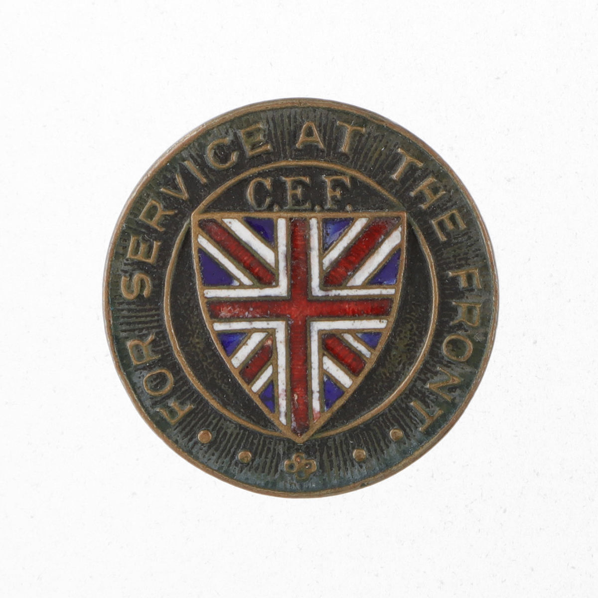 Épingle ronde en métal portant l’inscription en anglais « Pour le service au front, C.E.F » sur le pourtour, avec au centre un drapeau de l’Union Jack sur un bouclier Tudor.