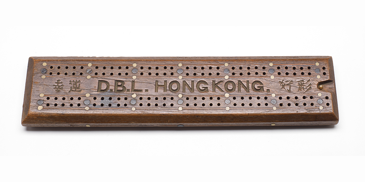 Plateau de jeu en bois avec l’inscription « D.B.L. Hong Kong » et de l’écriture japonaise.