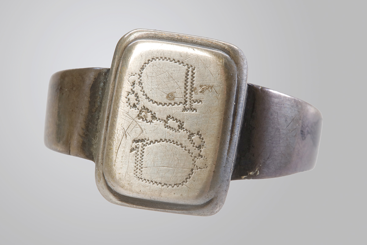 Gros plan d’une bague en argent avec gravure.