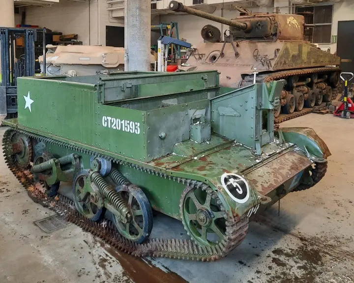 Un véhicule blindé vert, bas et carré, pourvu de chenilles. Il présente de nombreuses traces de rouille sur l’avant, les chenilles et les roues.