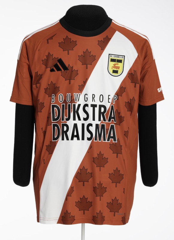 Tee-shirt de sport orange-marron à manches courtes, orné d’un motif répétitif de feuilles d’érable, avec une large bande blanche en diagonale et une inscription en gros caractères indiquant « Bouwgroep Dijkstra Draisma ».