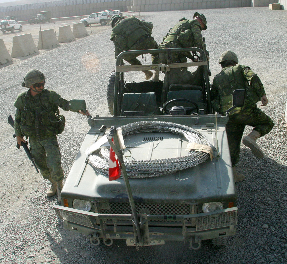 Quatre militaires sortent simultanément dans toutes les directions d’un véhicule de type Jeep, à toit et parois ouverts.