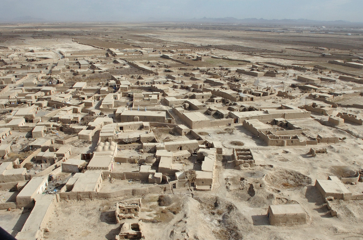 Une étendue de constructions basses et brunes ainsi que de murs disposés de façon irrégulière sur un paysage plat.